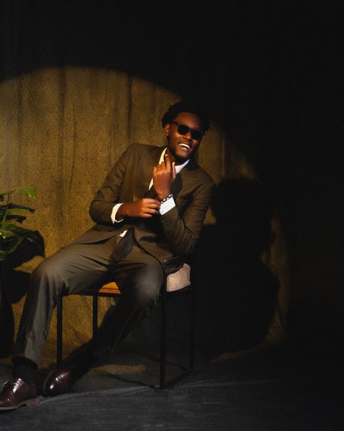 Free Confident man in suit and sunglasses sitting under dramatic spotlight. Stock Photo