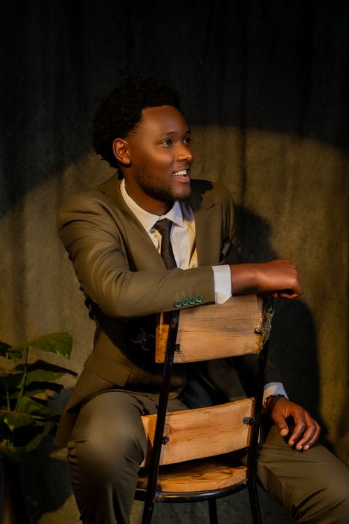 Free Portrait of a young man in a suit sitting on a chair with a warm smile. Stock Photo