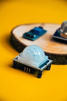 Close-up of electronic sensor module and circuit board on vibrant yellow backdrop.