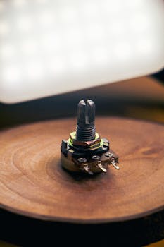 Detailed view of a potentiometer placed on a wooden surface with defocused lighting.
