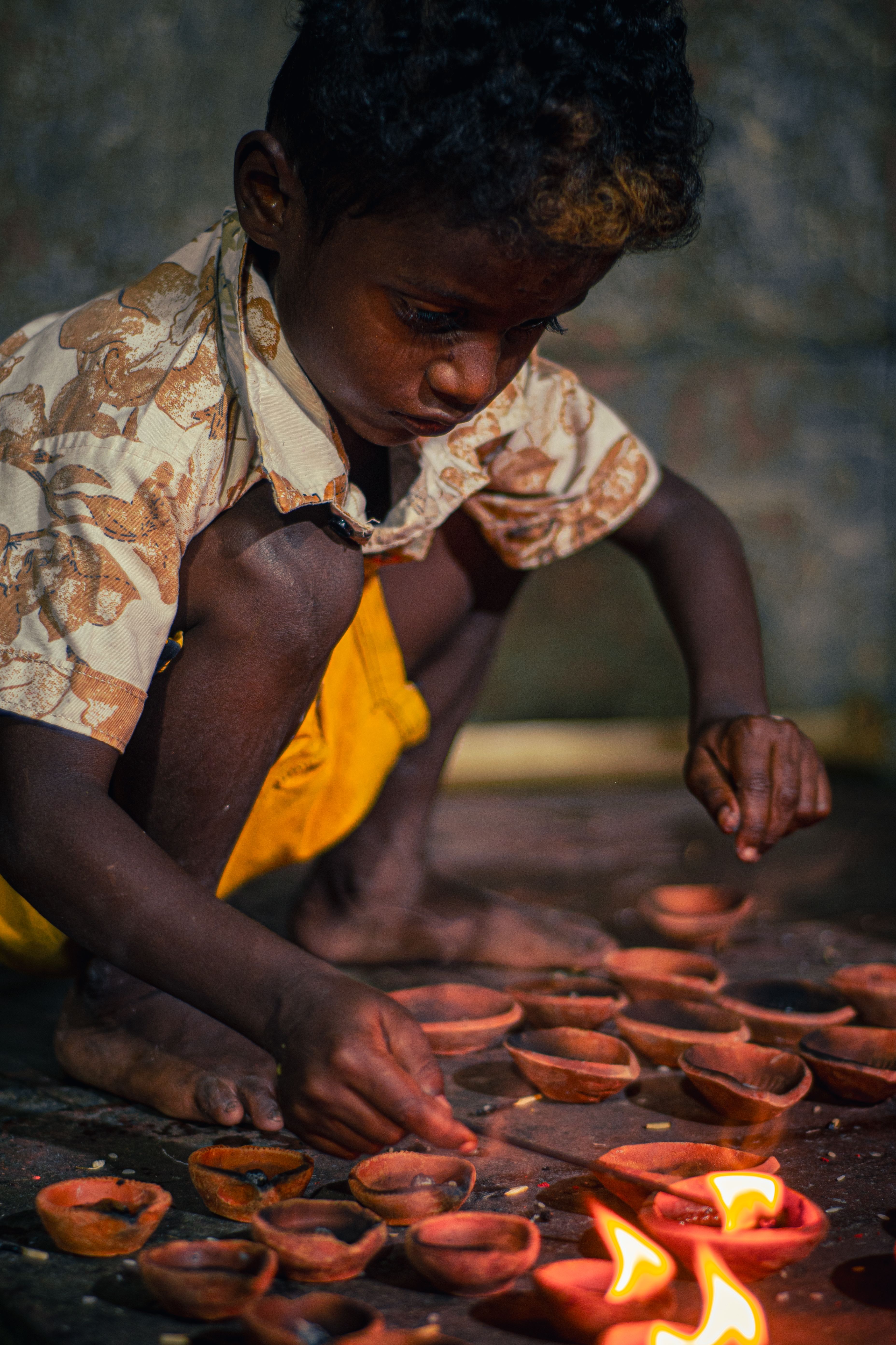 A young child lighting traditional clay lamps in Kolkata, India, showcasing cultural authenticity.