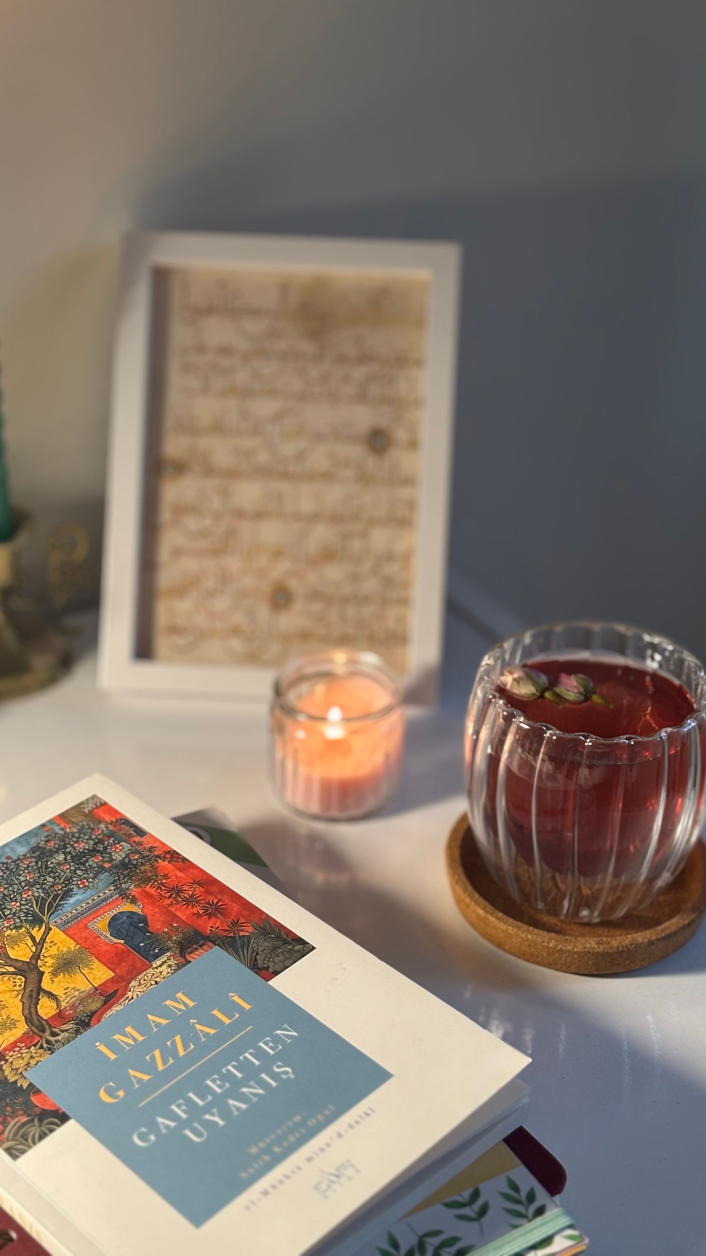 Cozy atmosphere with a candle, framed art, and a book on a table.