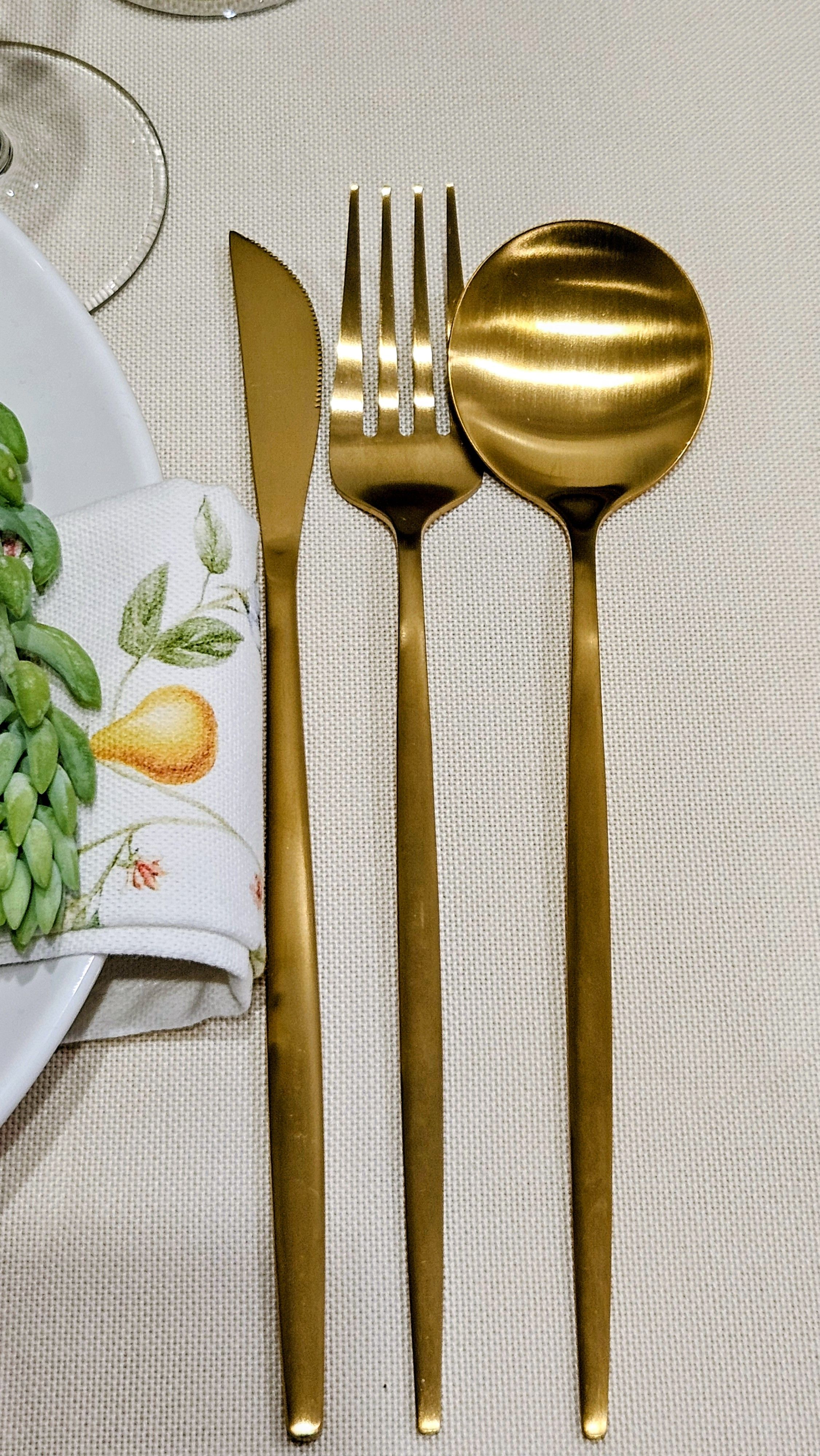 Talheres dourados elegantes dispostos com requinte em uma mesa de jantar refinada, para uma experiência gastronômica sofisticada.