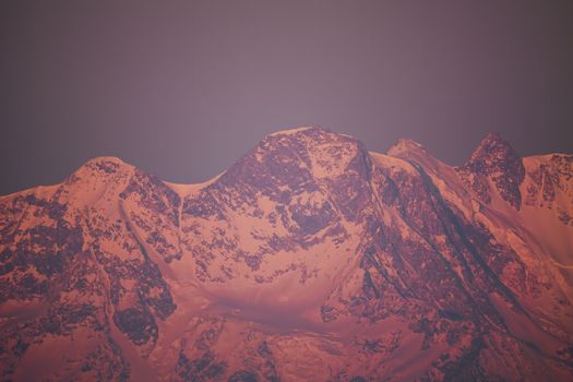 Stunning view of snow-capped mountains bathed in warm sunset hues, capturing nature's beauty.