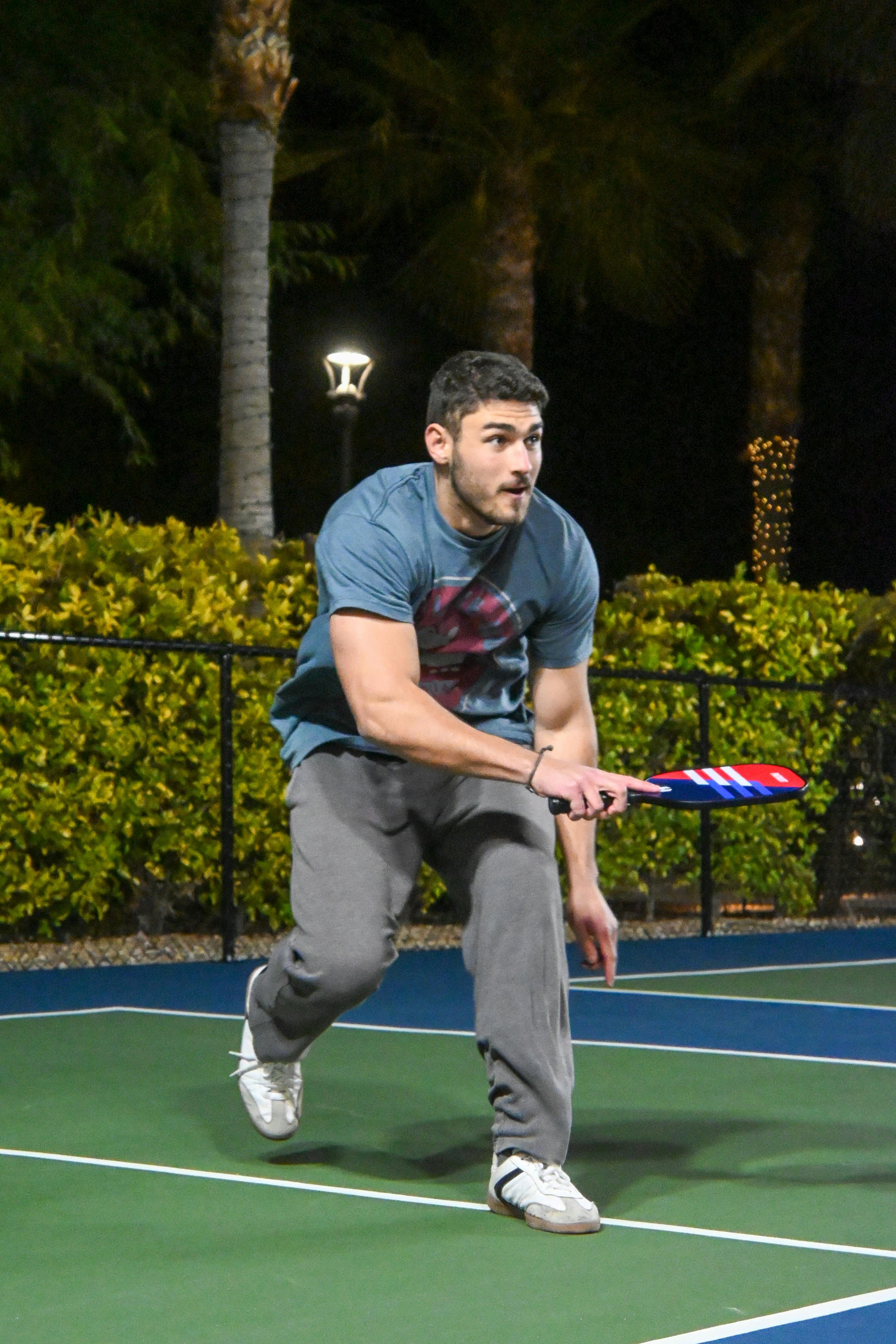 Male player in action on a Scottsdale pickleball court at night.