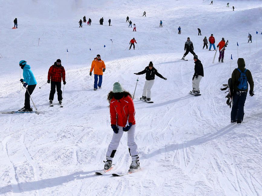 People skiing on a snowy slope in Bursa, Türkiye, enjoying winter sports under clear skies.