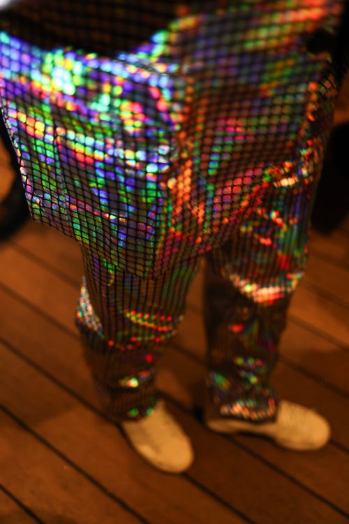 Free Vibrant holographic pants reflecting colorful light patterns on a wooden floor. Stock Photo