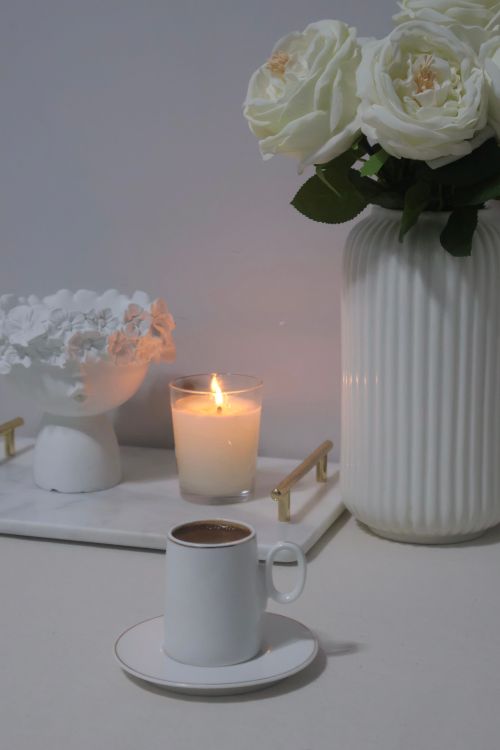 Free Elegant white setup with coffee, roses, and candle creating a serene ambiance. Stock Photo