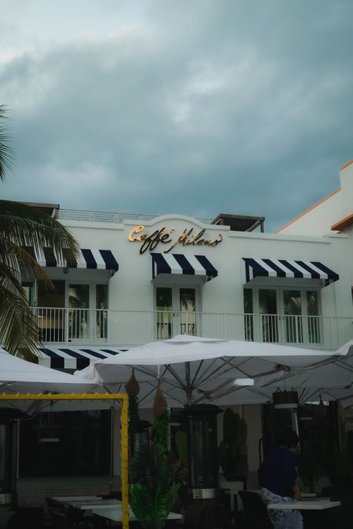 Free Elegant cafe with striped awnings under a moody sky, offering outdoor seating. Stock Photo