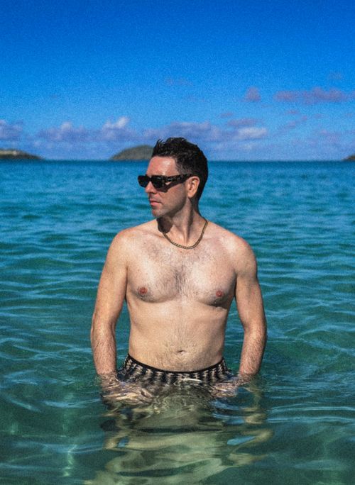 Free Shirtless man enjoying the ocean on a sunny day, wearing sunglasses and necklace. Stock Photo