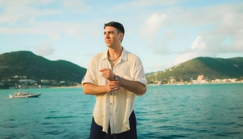 Free Man standing by the sea with scenic mountains. Perfect for travel inspiration. Stock Photo