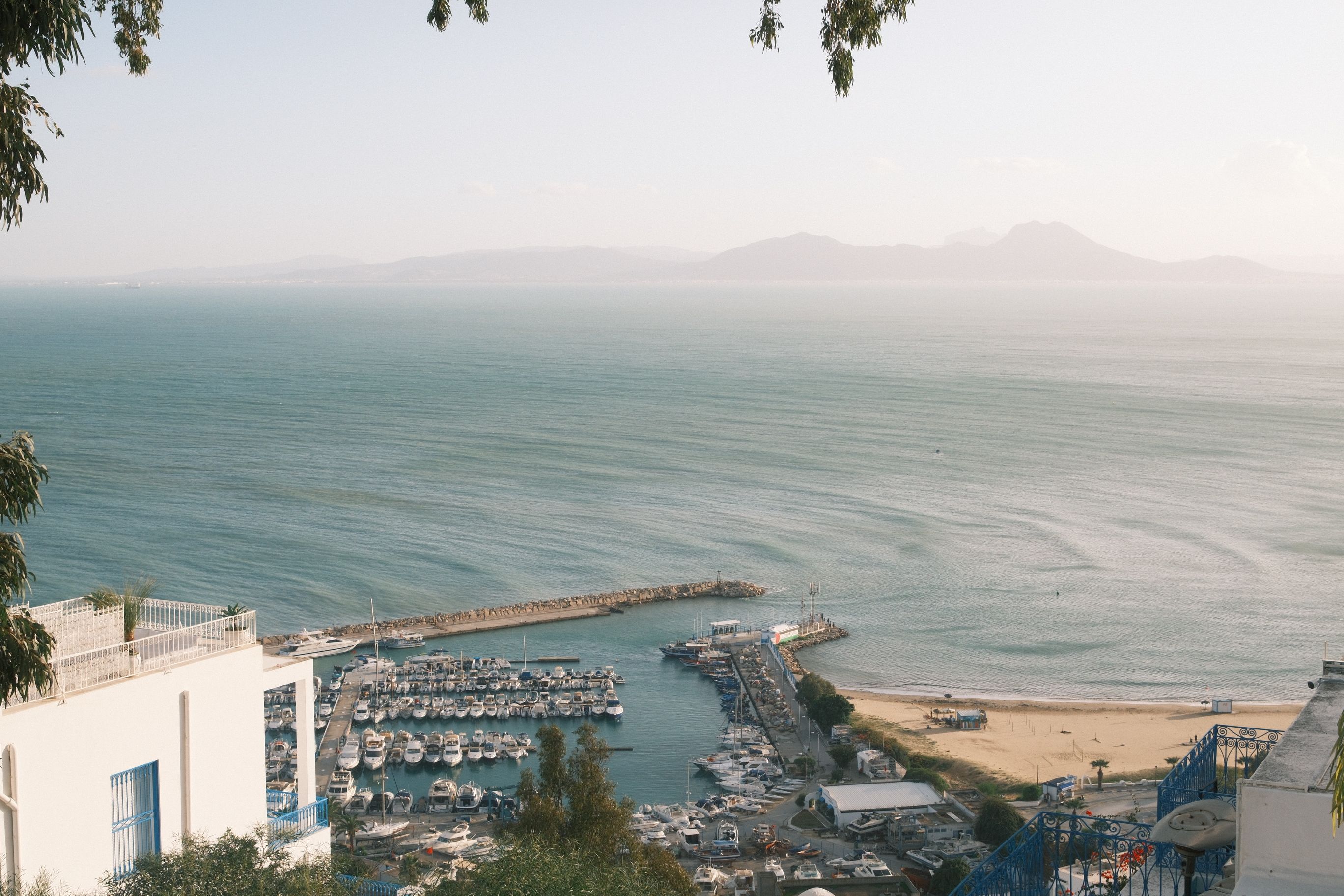 Serene view of the Gulf of Tunis from Carthage, showcasing a marina and calm sea under a clear summer sky.