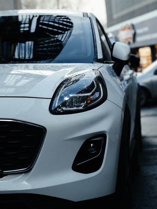 Free Close-up of a white car in an urban environment, showcasing its sleek design. Stock Photo