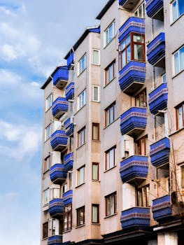 A modern apartment building showcasing unique blue balconies against a clear sky.