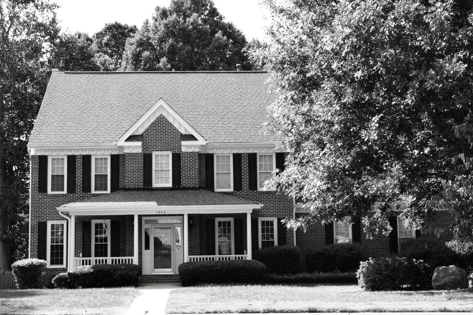 Black and white photo of a colonial brick house surrounded by trees in North Carolina.