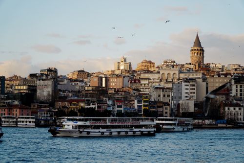 Free Scenic view of Istanbul's Galata Tower and skyline with boats on the Bosphorus at sunset. Stock Photo