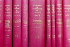 A row of red hardcover books titled 'Abridgments of Specifications of Patents'.