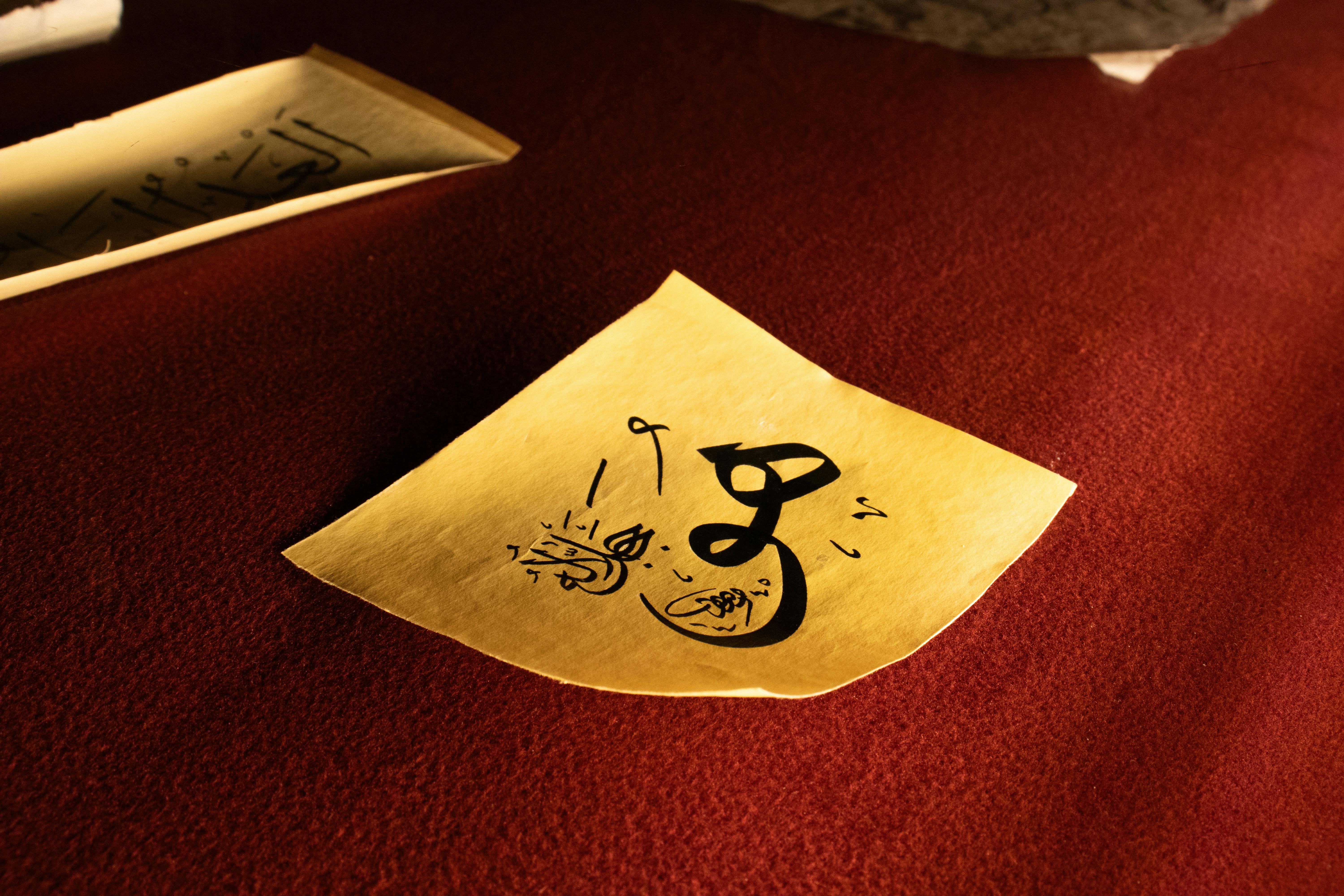 grátis Desenho caligráfico intrincado em papel amarelo sobre um fundo vermelho intenso. Foto profissional