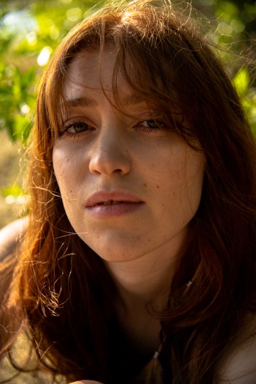 Free Portrait of a young woman with red hair enjoying a sunny day outdoors in Estonia. Stock Photo