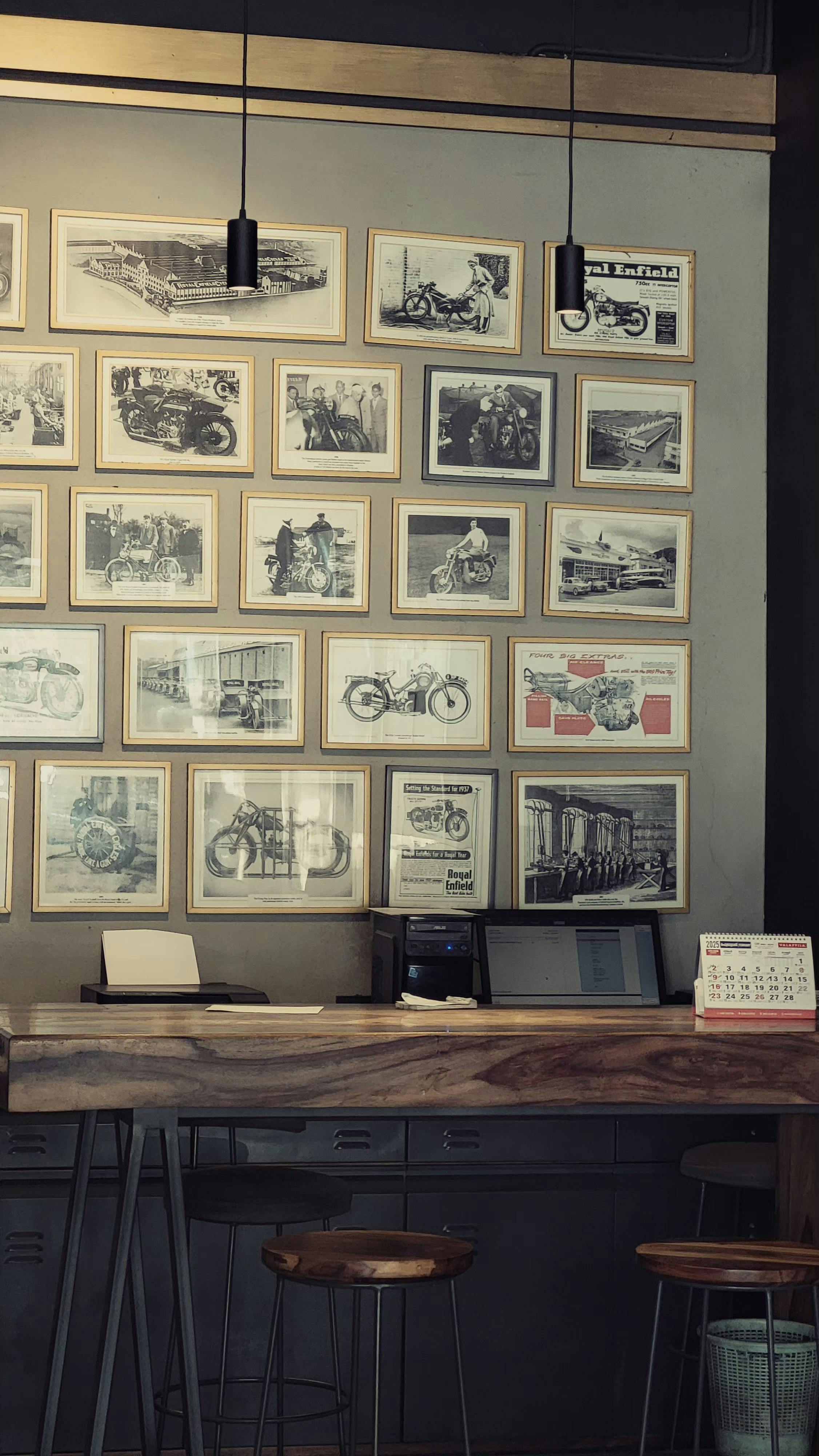 Cozy café interior with framed motorcycle photographs, wooden counter, and stools.