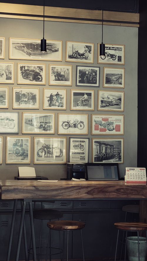 Free Cozy café interior with framed motorcycle photographs, wooden counter, and stools. Stock Photo
