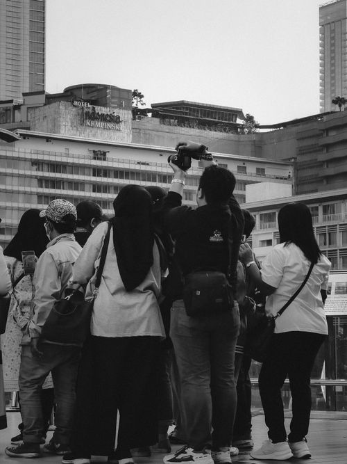 Free Tourists capture vibrant city skyline view with smartphones and cameras. Stock Photo
