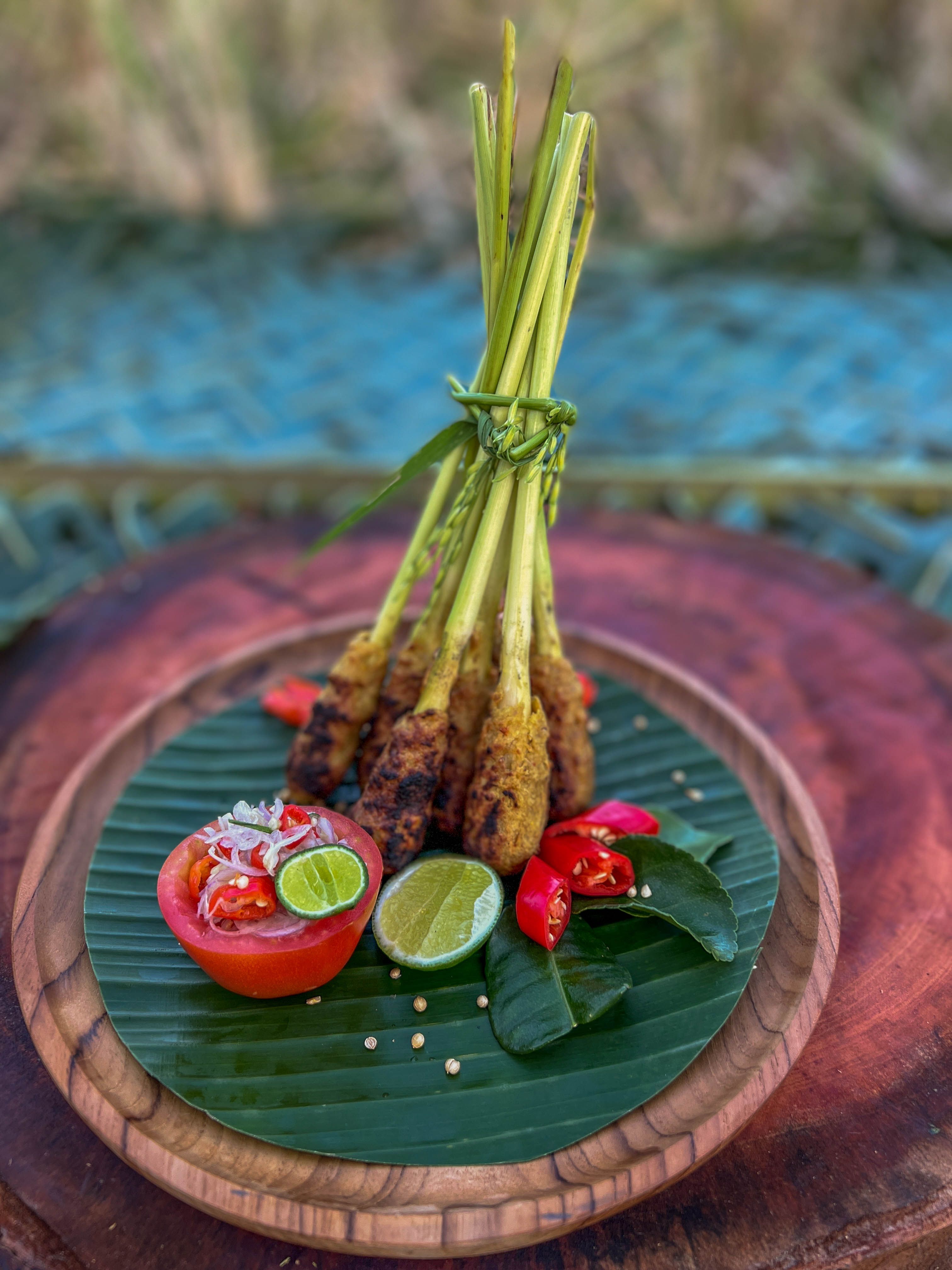 Sate lilit minced fish skewers wrapped on lemongrass stalks grilling over coconut-husk coals at a street stall in Bali