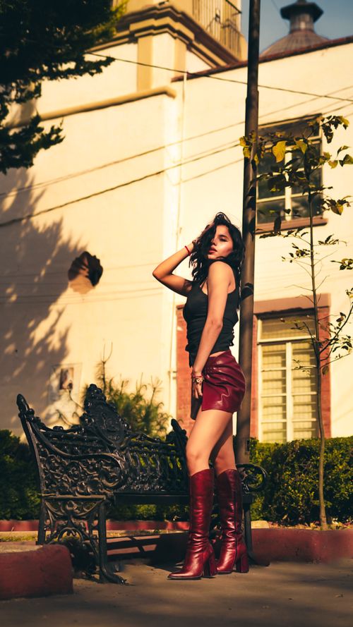 Free Stylish woman in red leather boots posing outdoors under warm sunlight. Stock Photo