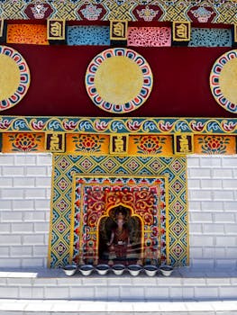 Vibrant temple wall with Buddhist iconography in Mechuka, showcasing intricate patterns and rich colors.
