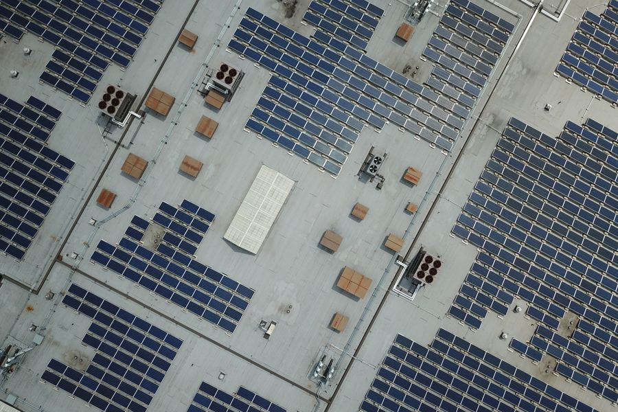 High-angle aerial shot of a large rooftop solar panel array on an industrial building.