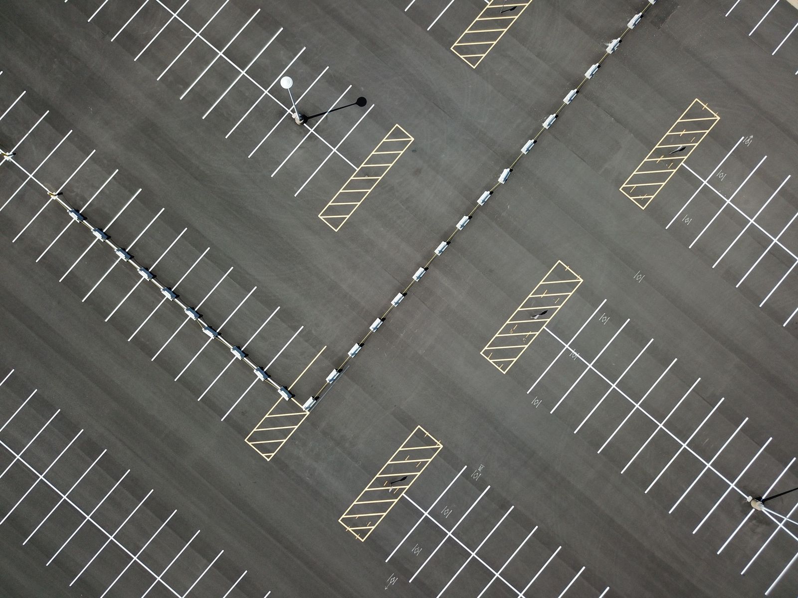 Wide aerial commercial parking lot with clear white stall lines and yellow no-parking zones