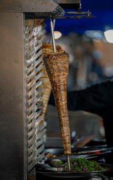 Juicy shawarma cooking on a vertical rotisserie at a street food stall in Kuwait, showcasing culinary tradition.