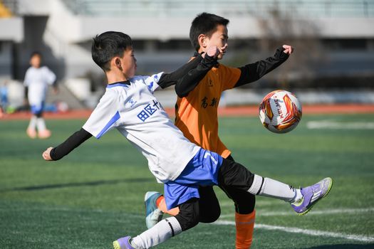 Two young boys competing energetically in a soccer match outdoors.