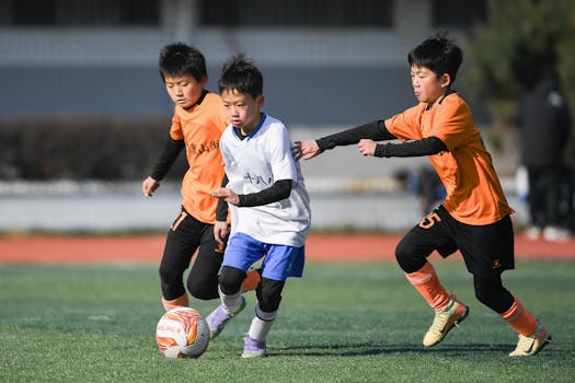Children playing a competitive soccer game outdoors on a sunny day.