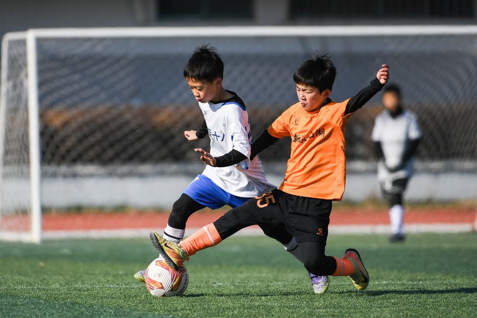 Two boys competing energetically in a youth soccer match outdoors.