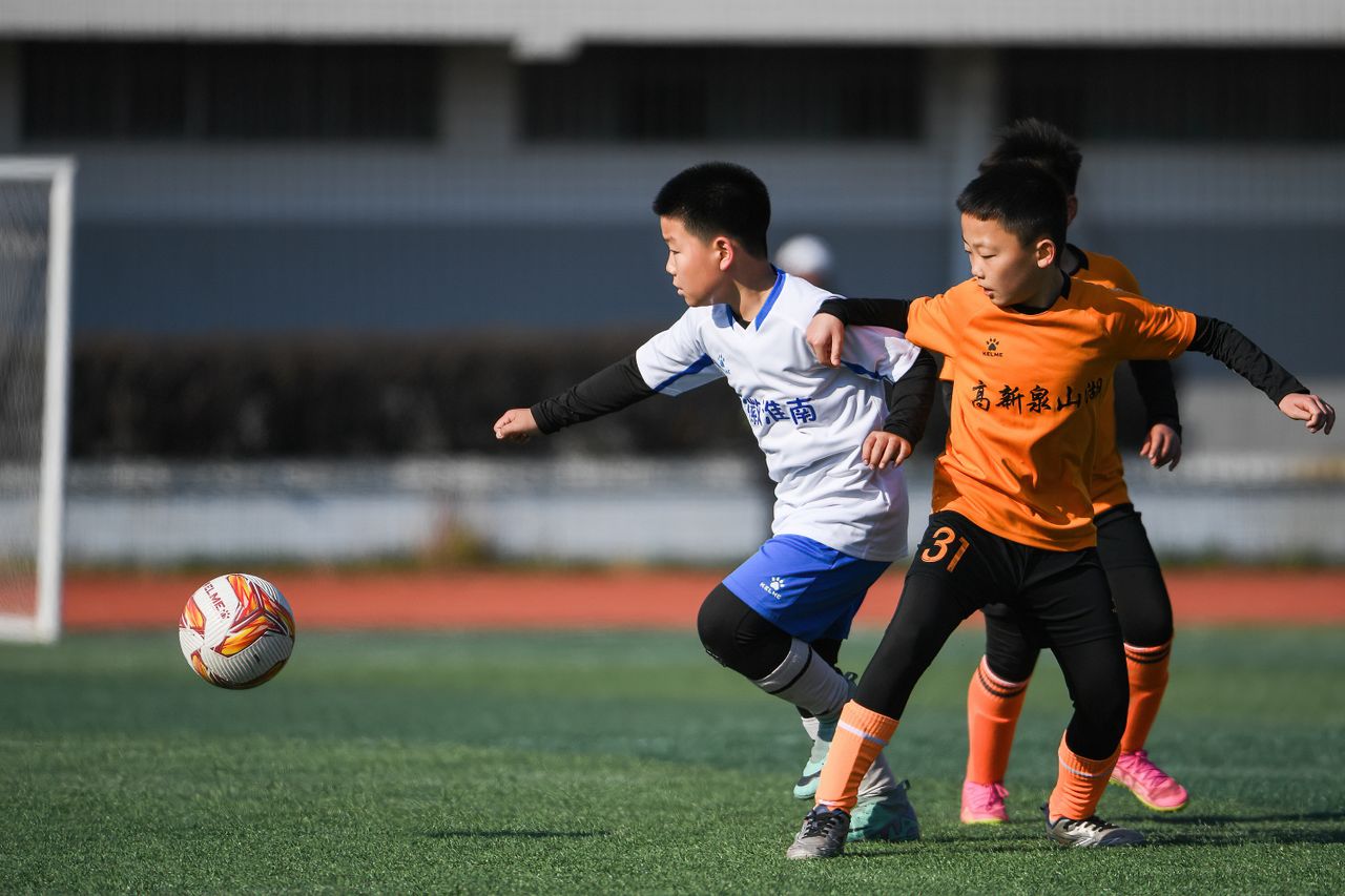children playing soccer on a sunny day competing for the ball on a spo