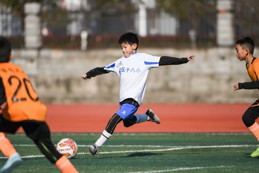 Boys playing a competitive soccer match on a sunny outdoor field.