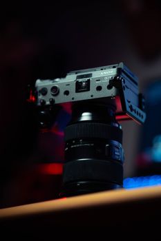 Close-up of a professional camera on a tripod in a dim studio setting.