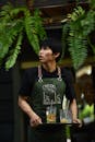 Young Server Carrying Drinks in Open-Air Cafe