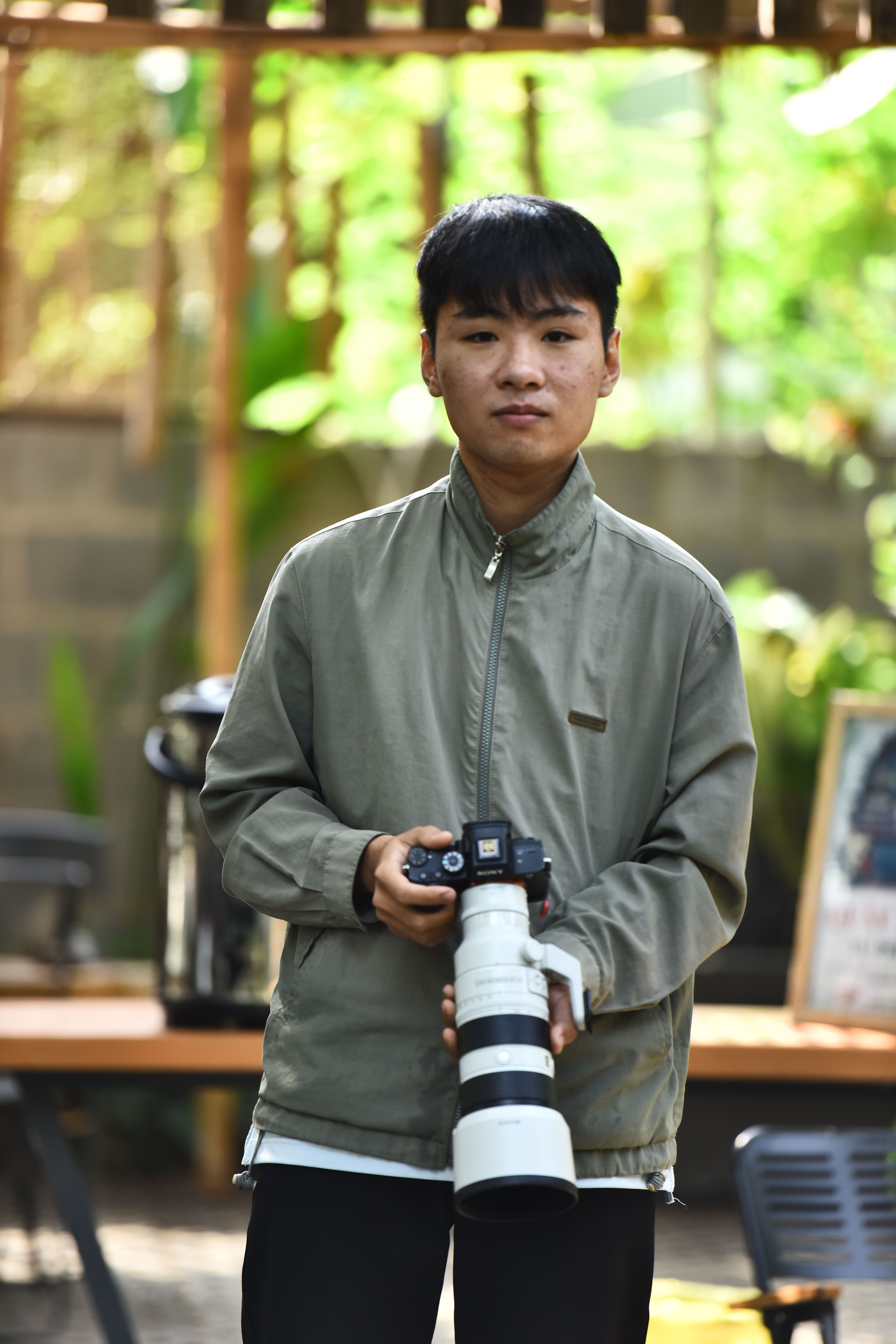 Young male photographer with a professional camera lens outdoors.