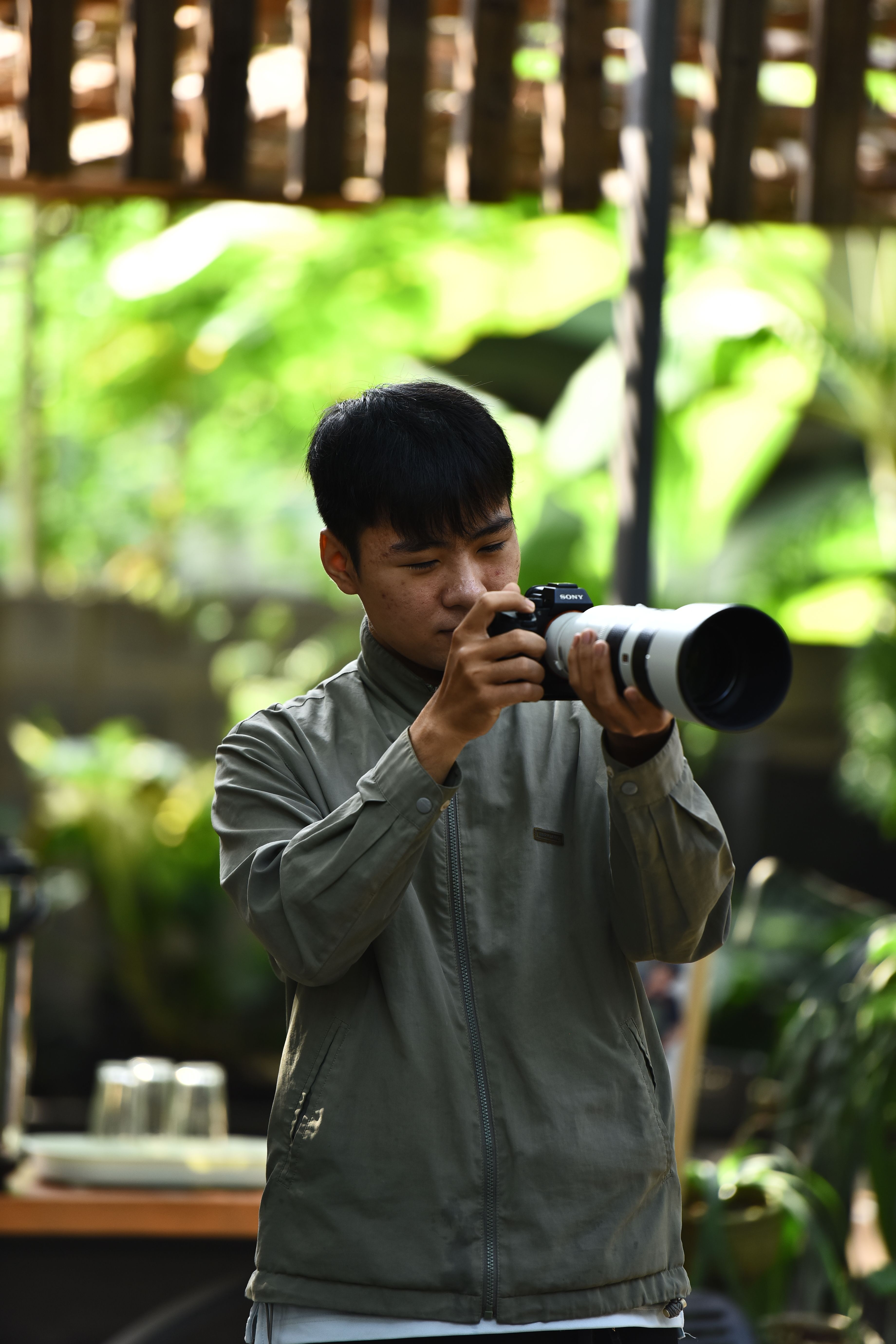 A man focuses a camera in a lush outdoor environment, perfect for nature photography.