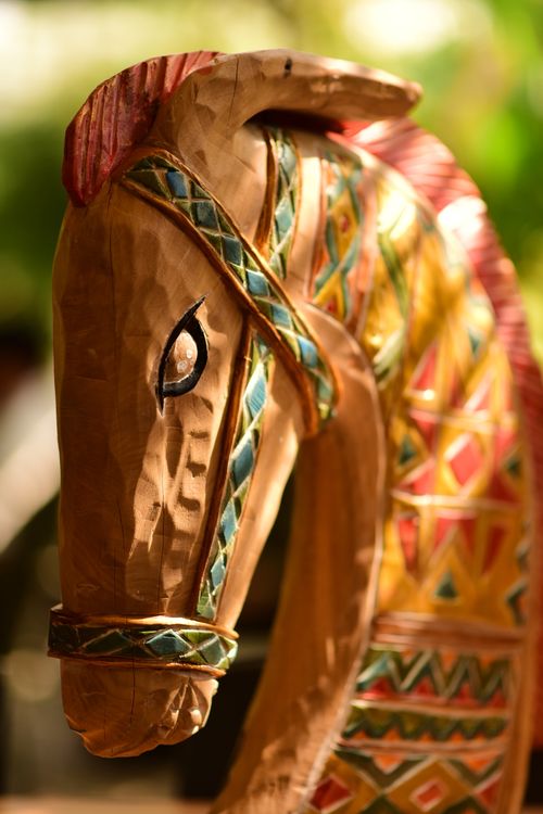 Free A colorful, detailed wooden horse sculpture highlighted by warm sunlight outdoors. Stock Photo