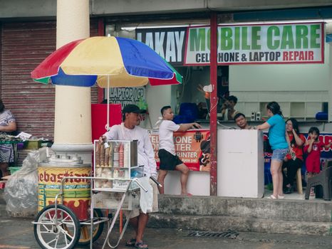 Street vendor selling ice cream under a colorful umbrella in NCR, Philippines, lively street scene.