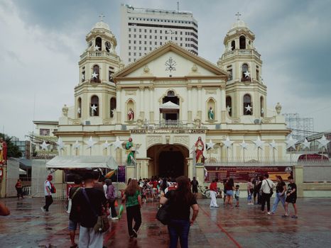 Stunning view of Quiapo Church, Manila, with visitors and a backdrop of skyscrapers.