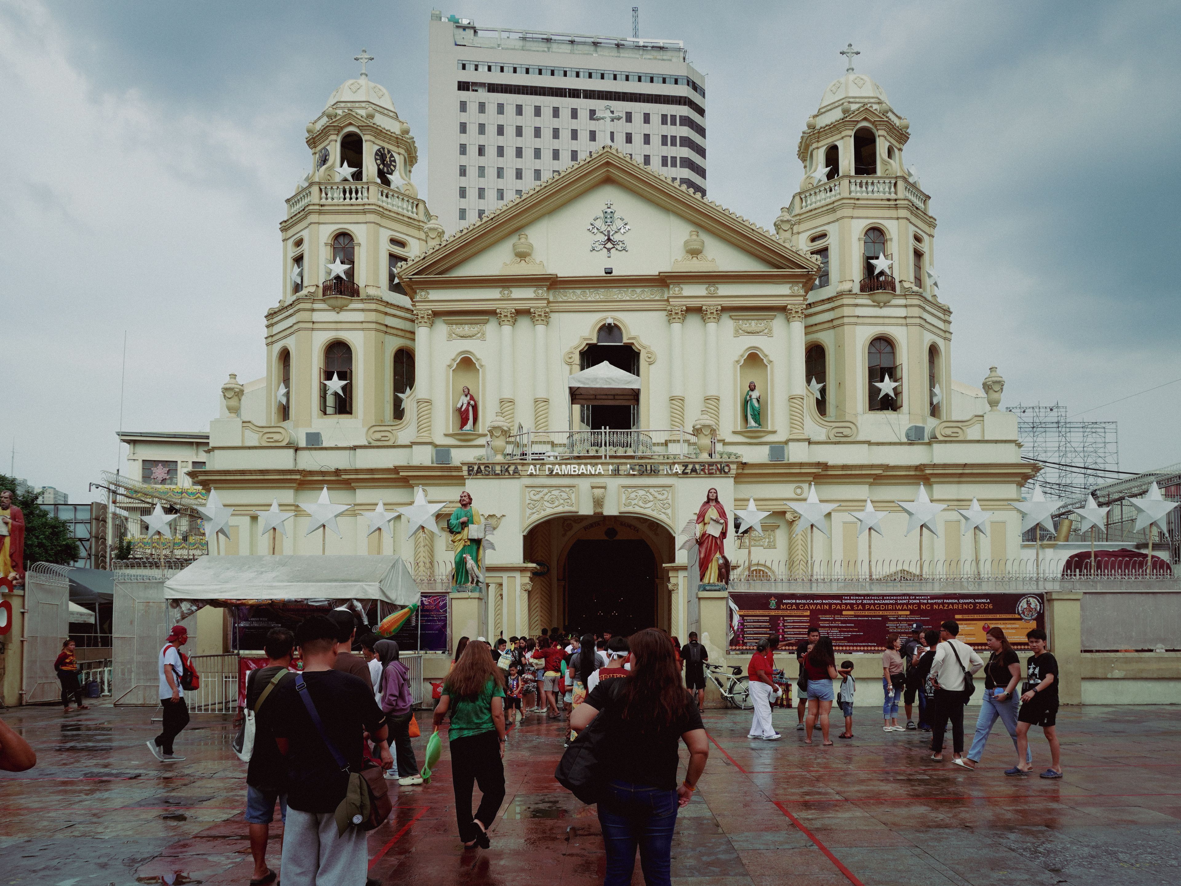 Stunning view of Quiapo Church, Manila, with visitors and a backdrop of skyscrapers.
