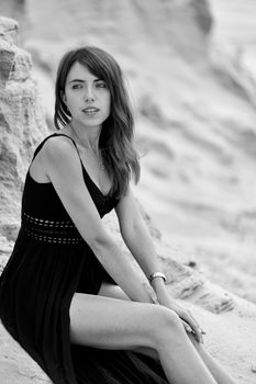 Elegant woman posing in a black dress against a rocky backdrop, captured in Lviv, Ukraine.