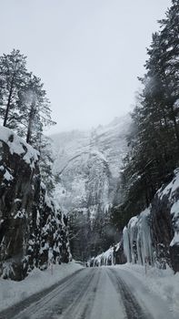 Snow-covered road winds through frozen cliffs in Tveitsund, Norway's winter landscape.