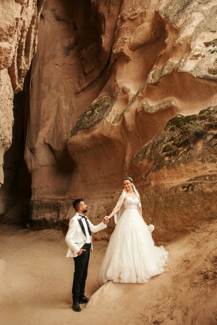 Bride and groom pose in elegant attire against Cappadocia's stunning rock formations.