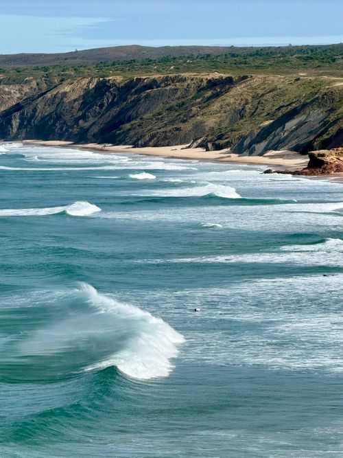 Free Stunning view of the Algarve coastline with rugged cliffs and rolling ocean waves under a clear blue sky. Stock Photo