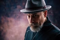 引人注目的特写中，一位戴着软呢帽、留着长胡子的男人，散发着严肃的风格